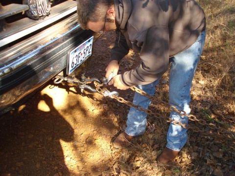 2008 International School Bus - A man secures chains to the front of a vehicle, preparing it for towing or recovery.