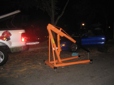 1993 Ford Probe - Engine hoist set up next to a blue car and a white pickup truck at night.