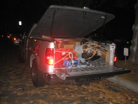 1993 Ford Probe - A pickup truck bed is loaded with an engine, boxes, and other items, with the tailgate down.