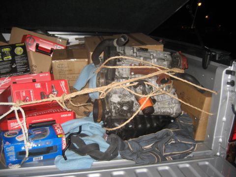 1993 Ford Probe - An engine and various tools are secured with rope in the bed of a pickup truck.