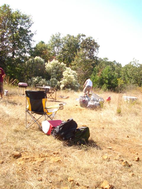 2008 International School Bus - An outdoor gathering with people, camping chairs, and bags scattered across dry, grassy terrain under a clear sky.