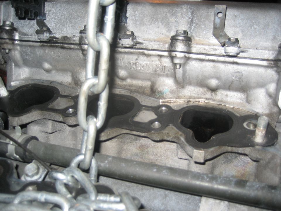 Engine block with intake manifold gasket and chain. Text 'TAKE' is visible