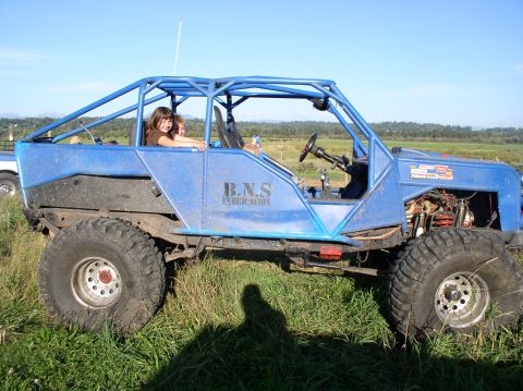1979 Ford Bronco - A custom-built buggy with a prominent roll cage sits in a grassy field under a clear blue sky.