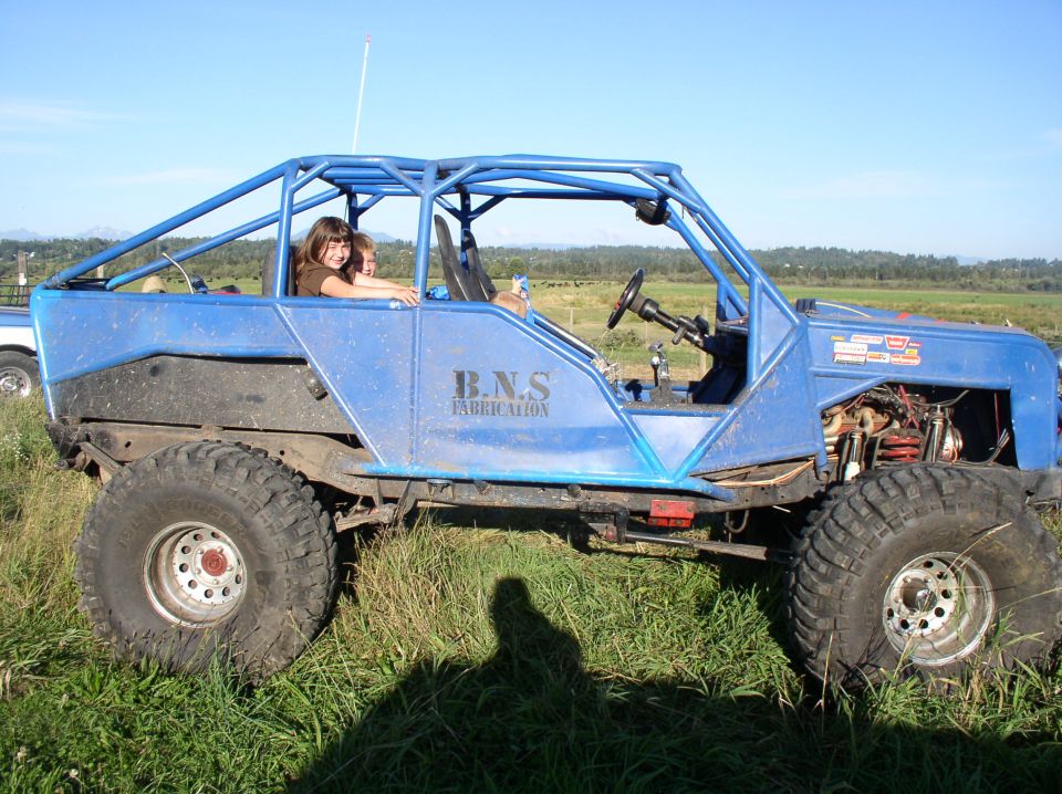 Blue custom buggy with roll cage and large tires, two people inside