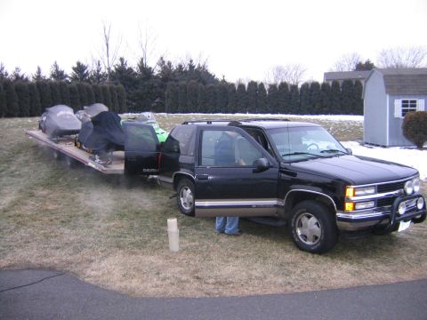 1998 Chevrolet Tahoe - 1998 Chevrolet Tahoe is seen towing two snowmobiles on a trailer in a yard.