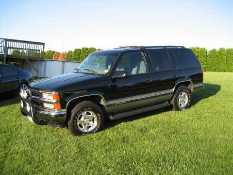 1998 Chevrolet Tahoe - A black SUV is parked on a grassy lawn with a wooden deck in the background.