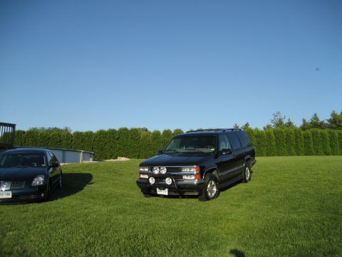 1998 Chevrolet Tahoe - A black 1998 Chevrolet Tahoe is parked on a lawn next to another vehicle under a clear blue sky.