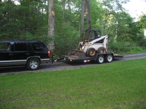 1998 Chevrolet Tahoe - A black 1998 Chevrolet Tahoe is seen from the side, towing a trailer loaded with a skid steer loader.