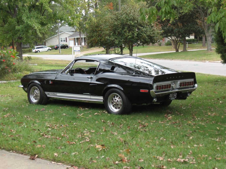 Black 1968 Shelby GT500 parked on grass, rear quarter view