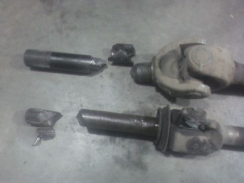 1992 Ford F-350 - Damaged driveshaft parts lie on a concrete floor, indicating a mechanical failure.