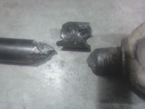 1992 Ford F-350 - A close-up view of a broken metal component and a piece of rubber debris on a concrete surface.