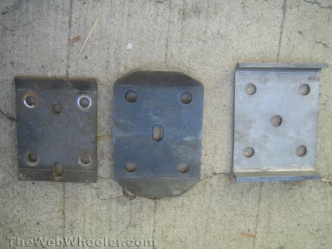 1987 Suzuki Samurai - Three metal leaf spring plates with varying hole patterns are laid out on a concrete surface.