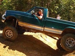 2008 International School Bus - Pickup truck with lifted suspension on a dirt hill.