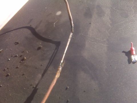 1986 Ford Bronco - Two wires are taped together, with a small red cap visible to the right on a dark, textured surface.