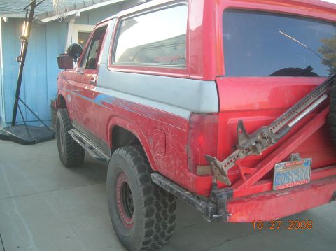 1985 Ford Bronco - This 1985 Ford Bronco features a two-tone red and silver paint scheme and a Hi-Lift jack mounted on its custom rear bumper.