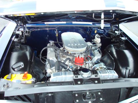 1977 Ford F-100 - The engine bay of a blue vehicle, a V8 engine with chrome accents and a prominent air cleaner.