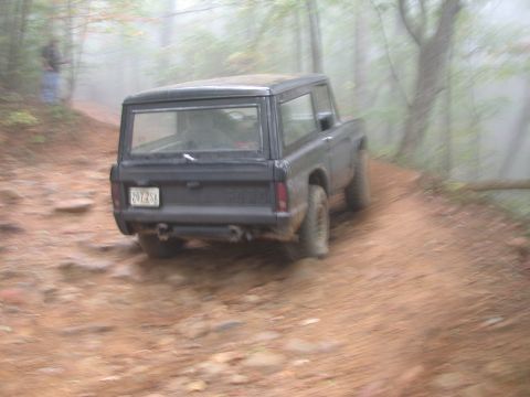 1972 Ford Bronco - A black 1972 Ford Bronco navigates a foggy, wooded dirt road.