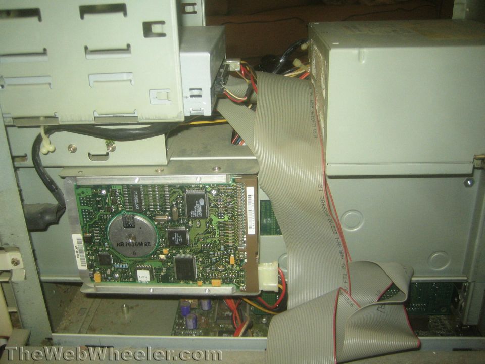 Inside of a computer tower showing a circuit board, ribbon cable, and power supply