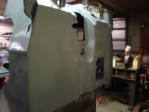 1948 Jeep Wrangler - Unfinished vehicle body in primer, likely undergoing repair or restoration work in a garage setting.