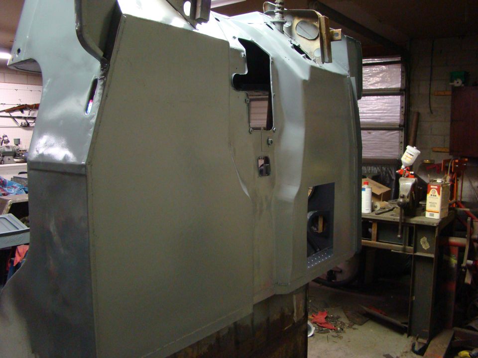 Gray vehicle body undergoing restoration, showing panel work and cutouts