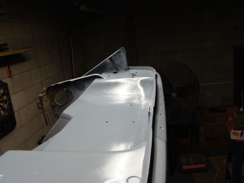 Primed vehicle body panel, possibly a fender or hood section, in a workshop