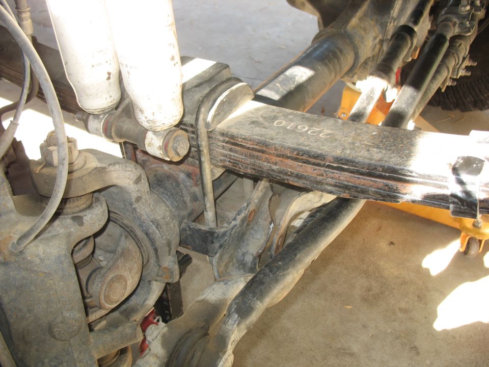 Front leaf-spring suspension with shocks and shackle viewed from below a truck