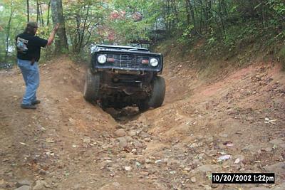 1972 Ford Bronco - A 1972 Ford Bronco tackles a challenging off-road trail with a driver observing.