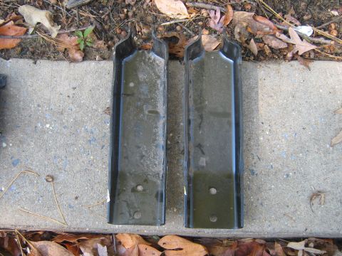 1990 Ford Bronco - Two metal brackets are shown lying on the ground next to some fallen leaves.