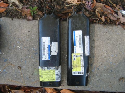 1990 Ford Bronco - Two black metal automotive parts with labels are shown on the ground.