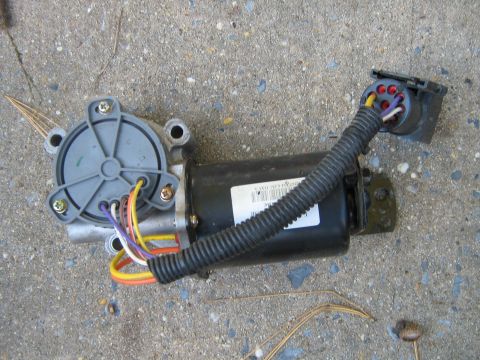 1990 Ford Bronco - This transfer case motor assembly includes a wiring harness and multi-pin connector, shown resting on a concrete surface.
