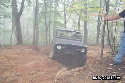1972 Ford Bronco - 1972 Ford Bronco navigating an off-road trail in a forest setting.