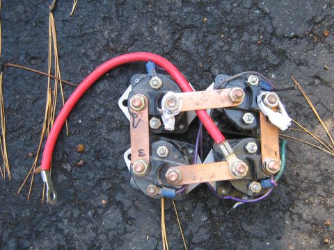 1990 Ford Bronco - A starter solenoid assembly, likely from a vehicle, lies on asphalt with pine needles.