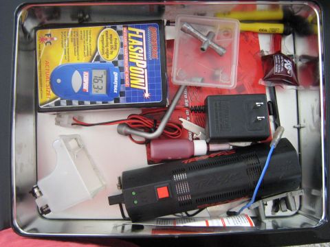 1990 Ford Bronco - Contents of a tin box include an RC car charger, a temperature gauge, and various tools.