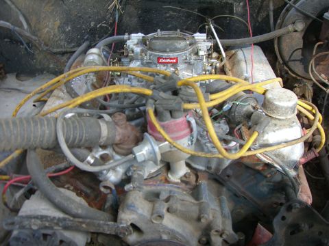 1988 Ford Bronco - Close-up view of a vehicle's engine bay, a carburetor and yellow spark plug wires.