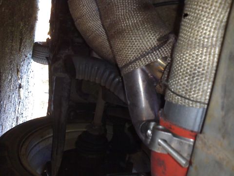 1993 Ford Probe - Close-up view of exhaust manifold and piping, showing heat wrap and a red hose clamp. The registry claims 1993 Ford Probe, but this is not…