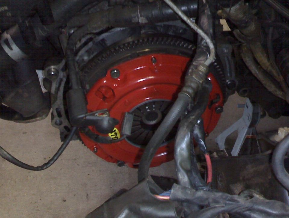 Close-up of a red clutch and flywheel assembly with wiring and engine components
