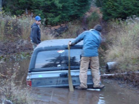 1988 Chevrolet Blazer - Two men attempt to free a gray SUV that is stuck deep in muddy terrain.