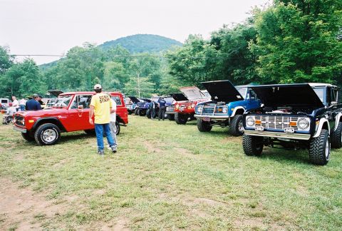 1972 Ford Bronco - A collection of Ford Broncos are gathered outdoors, with a staff member visible near a red model.