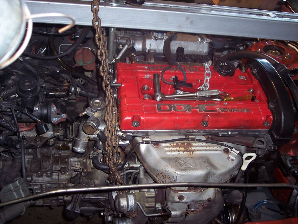 engine with red DOHC 16-VALVE cover, chain hoist attached, tools on top