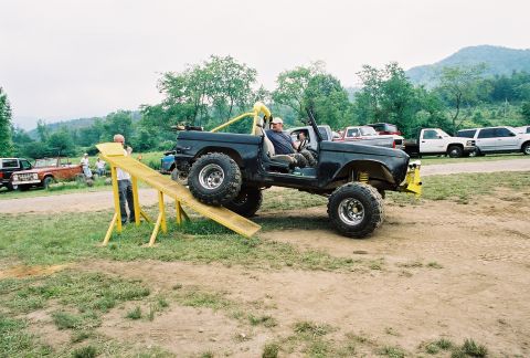 1972 Ford Bronco - A modified black Ford Bronco is positioned on a ramp with two people inside.
