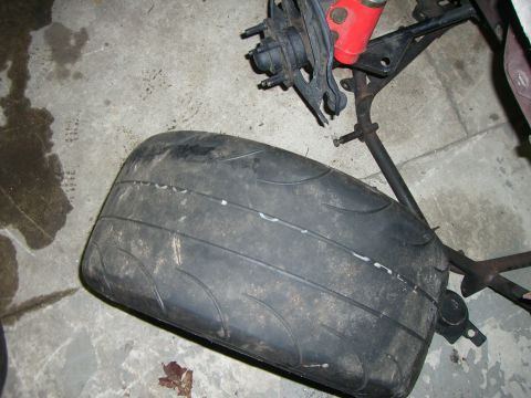 1988 Ford Bronco - Close-up of a used tire and part of a vehicle's suspension system.