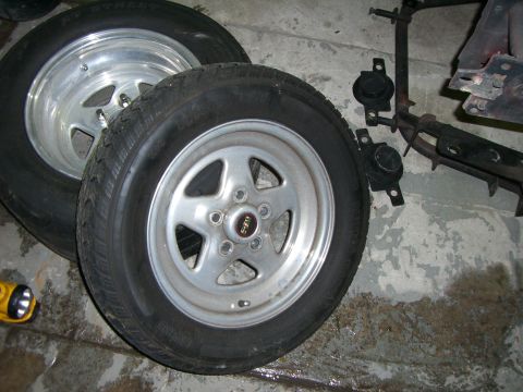1988 Ford Bronco - Two alloy wheels and tires are shown alongside suspension parts, possibly for a Ford vehicle.