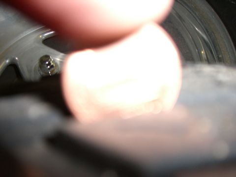 1988 Ford Bronco - A close-up view of a tire valve stem, with a finger partially obscuring the image.