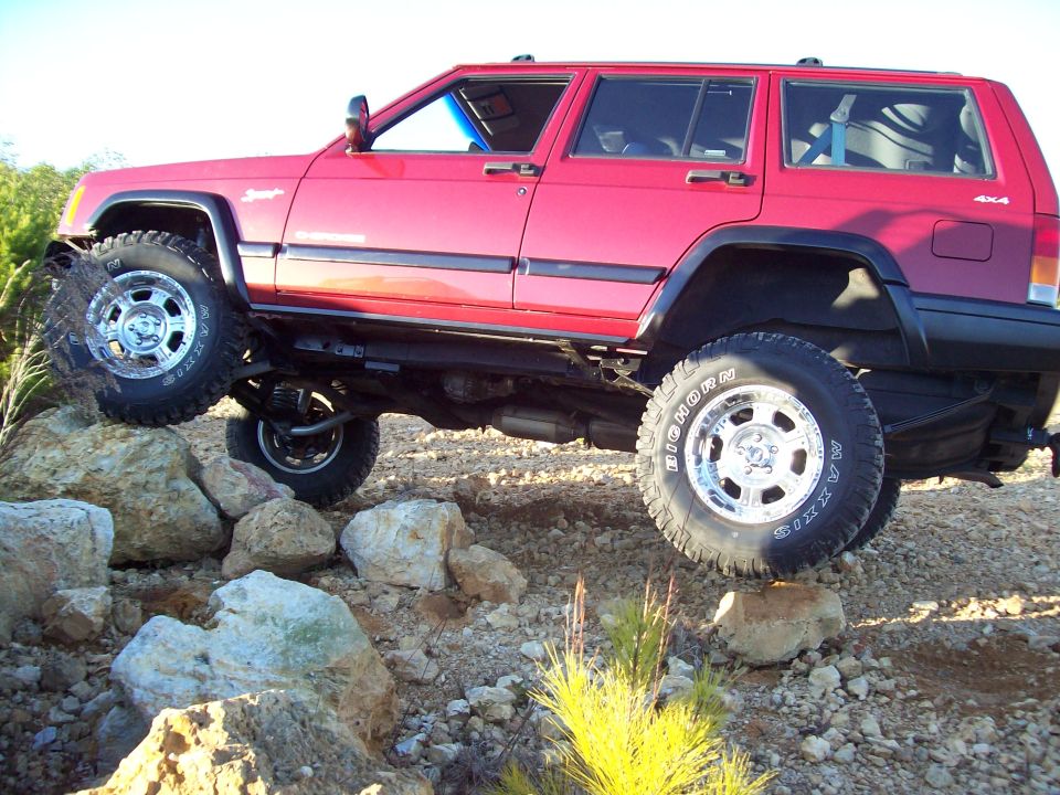 Red 1998 Jeep Cherokee climbing rocks, 3/4 front view
