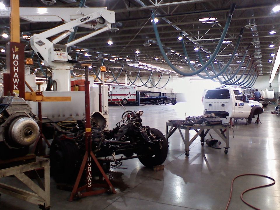 White pickup truck chassis with engine removed, in a workshop