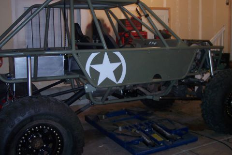 1995 Ford Bronco - A custom-built off-road buggy with a military-style star emblem is parked indoors.