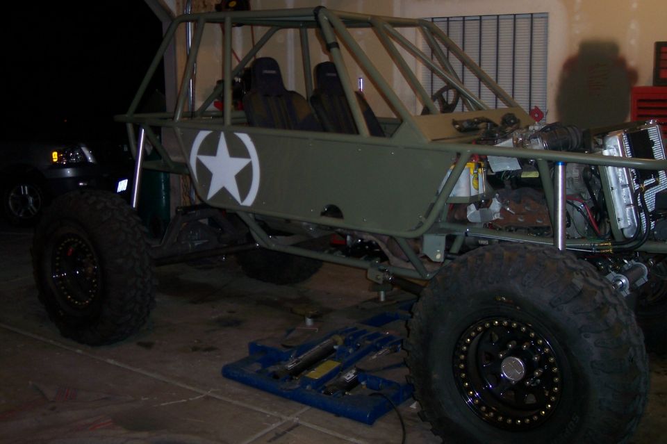 Olive drab buggy with white star decal, roll cage, and large off-road tires