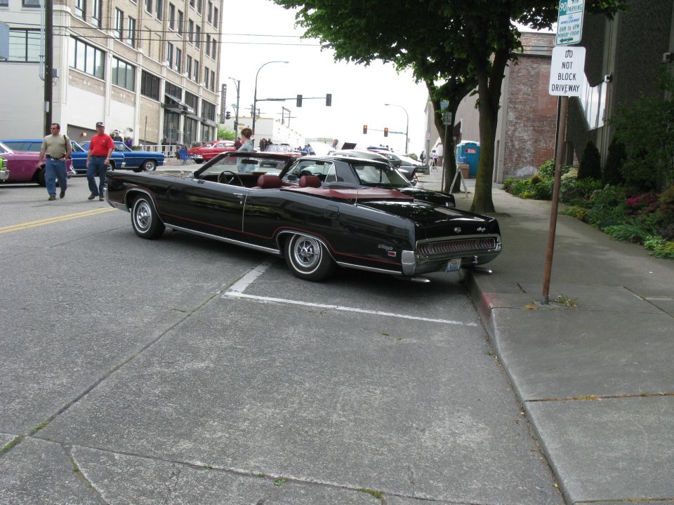 Black convertible with maroon interior parked at angle on city street