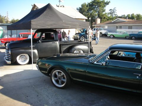 1998 Ford Crown Victoria - Several classic vehicles are parked outside under a tent and in the open.