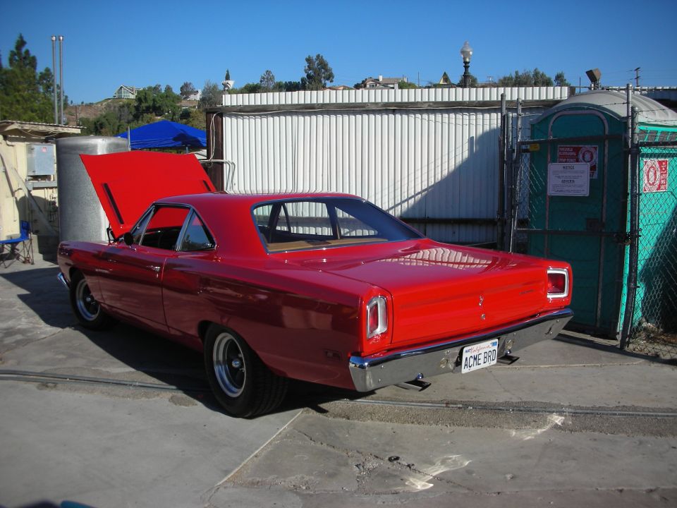 Red 1969 Plymouth Road Runner coupe with hood open, parked outdoors